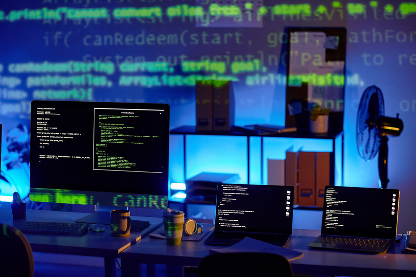 Row of laptops and computer monitor with decoded data on their screens Row of laptops and computer monitor with decoded data on their screens standing on workplace of contemporary diversity programmers
